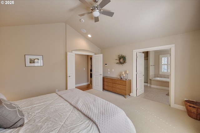 bedroom featuring lofted ceiling, baseboards, ensuite bath, light colored carpet, and ceiling fan