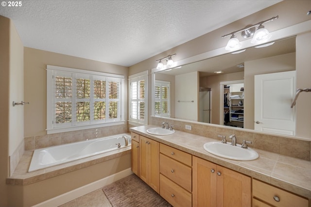 full bath with a sink, a garden tub, and a textured ceiling
