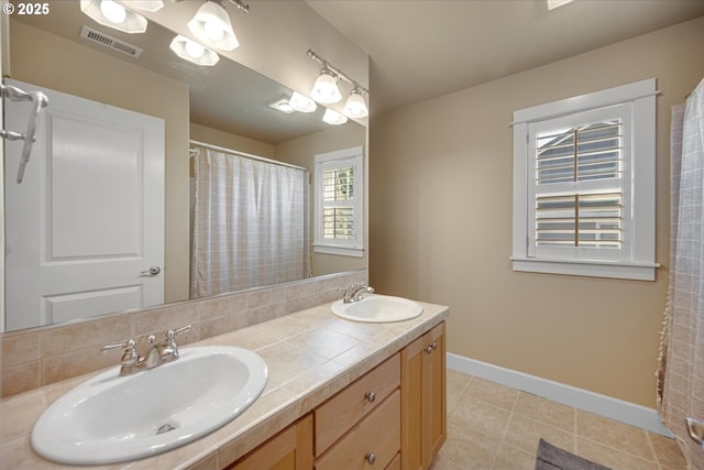 bathroom featuring baseboards, visible vents, a sink, and tile patterned floors