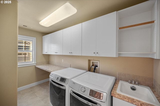 clothes washing area featuring visible vents, baseboards, a sink, washer and dryer, and cabinet space