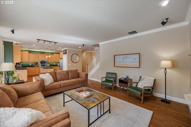 living area featuring visible vents, wood finished floors, stairway, and a textured ceiling