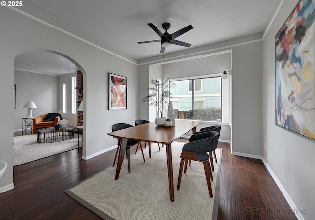 dining space featuring baseboards, ornamental molding, hardwood / wood-style floors, arched walkways, and a ceiling fan