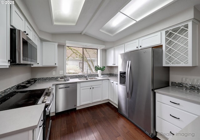 kitchen featuring dark wood-type flooring, a sink, white cabinetry, stainless steel appliances, and vaulted ceiling with beams