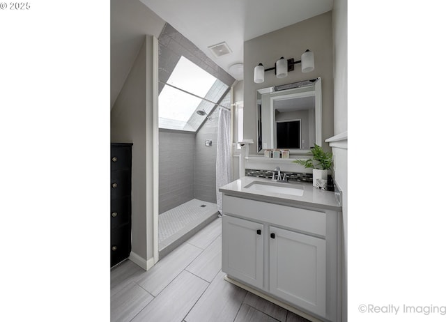 bathroom with a tile shower, visible vents, vanity, and wood finish floors