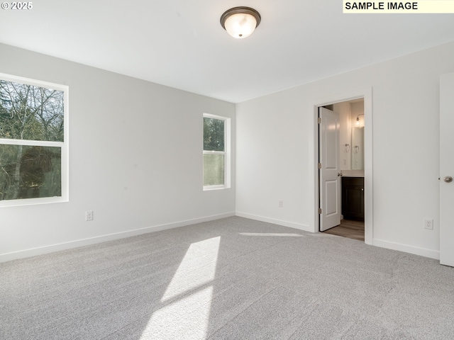 unfurnished bedroom with carpet floors, baseboards, and ensuite bath