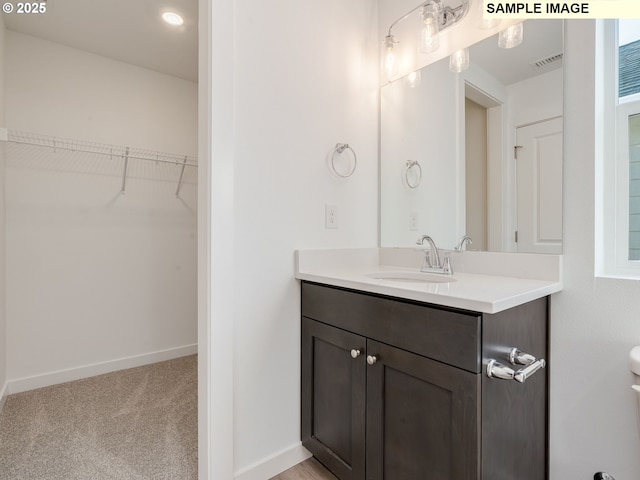 bathroom with vanity, a spacious closet, and baseboards