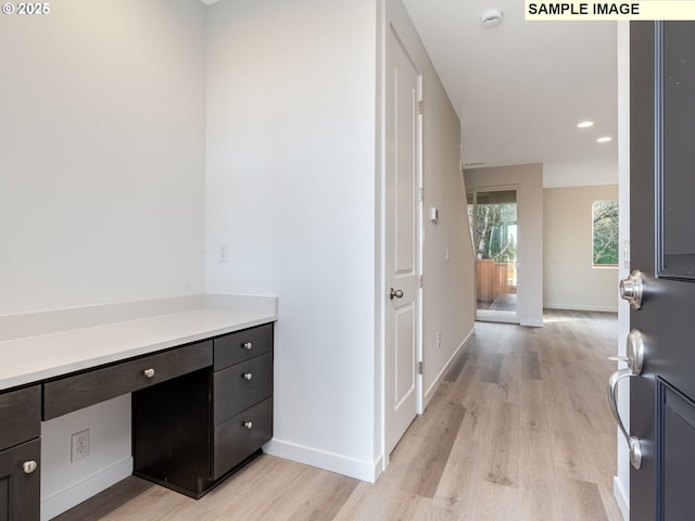 hall featuring light wood-type flooring, baseboards, and recessed lighting