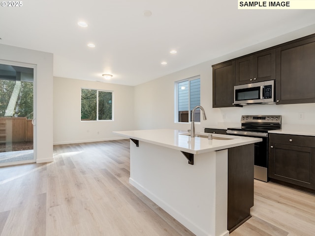 kitchen with appliances with stainless steel finishes, a sink, plenty of natural light, light wood-style floors, and recessed lighting