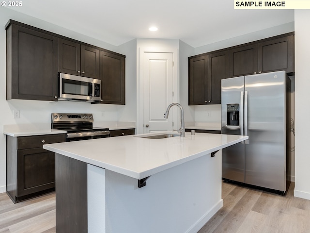kitchen featuring stainless steel appliances, a sink, light wood-type flooring, recessed lighting, and dark brown cabinets