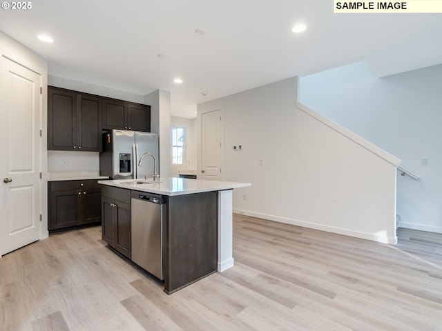 kitchen featuring appliances with stainless steel finishes, light countertops, light wood-style flooring, baseboards, and dark brown cabinets