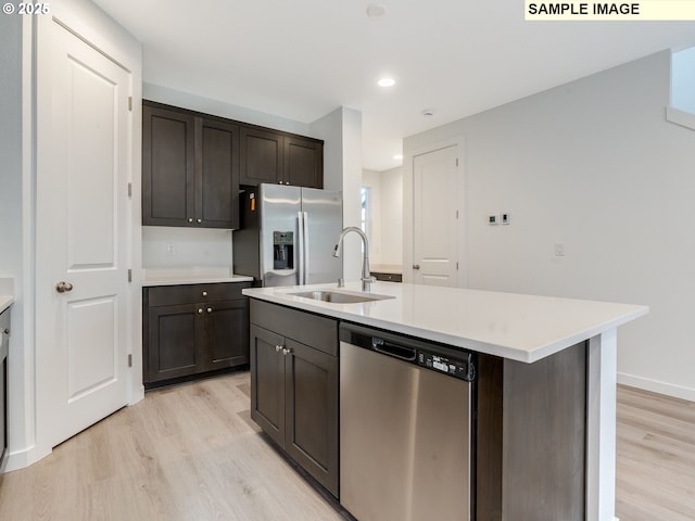 kitchen with appliances with stainless steel finishes, a sink, light wood-type flooring, light countertops, and dark brown cabinetry