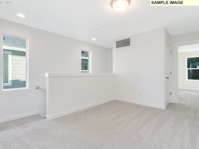 empty room with carpet, attic access, recessed lighting, and baseboards
