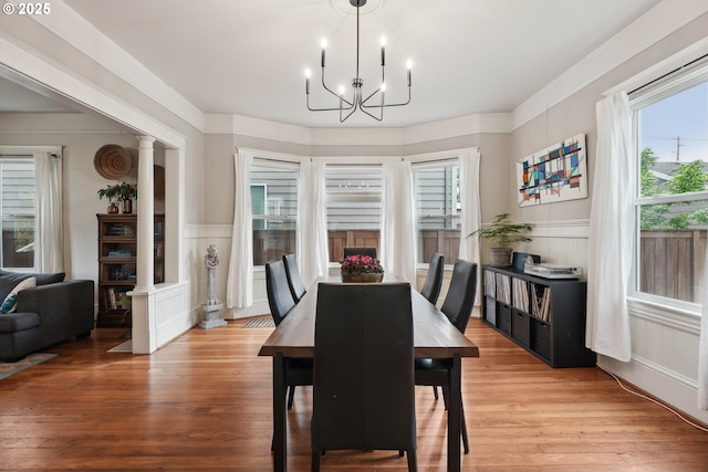 dining room featuring a chandelier, wainscoting, a decorative wall, healthy amount of natural light, and light wood-style floors