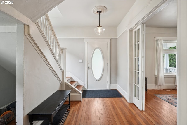 foyer entrance featuring stairway, wood-type flooring, and baseboards