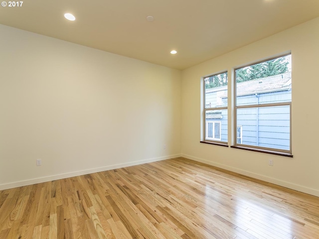 empty room with light wood-type flooring, baseboards, and recessed lighting