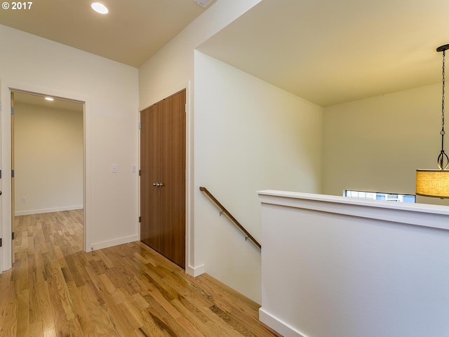 hall featuring visible vents, baseboards, an upstairs landing, light wood-style floors, and recessed lighting