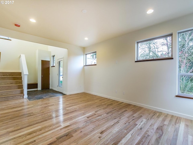 spare room with light wood-type flooring, baseboards, stairway, and recessed lighting