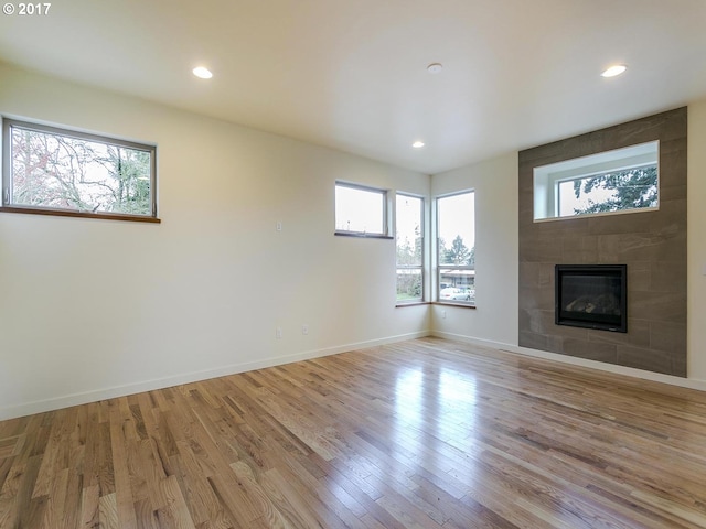 unfurnished living room with recessed lighting, baseboards, a fireplace, and light wood finished floors