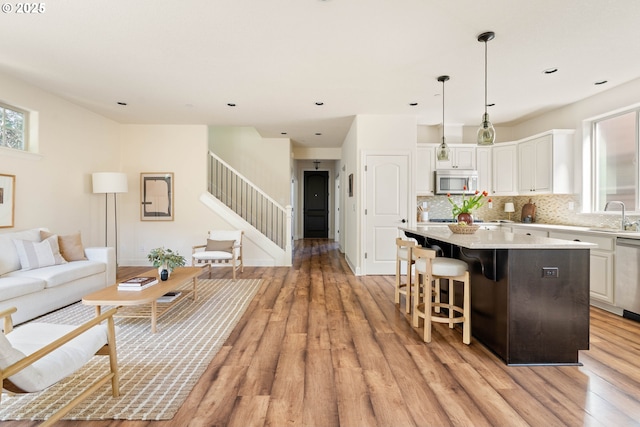 living room with light wood-style flooring, recessed lighting, baseboards, and stairway