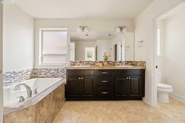 full bathroom featuring a sink, tile patterned floors, toilet, and a garden tub
