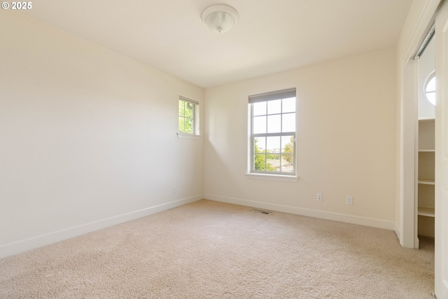 empty room featuring light carpet, visible vents, and baseboards