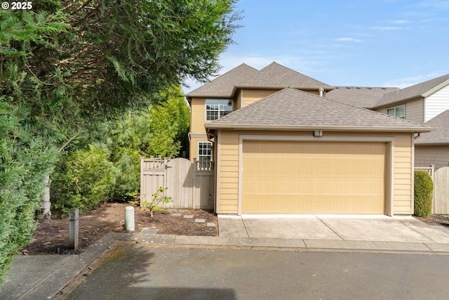 view of front of house with roof with shingles, fence, a gate, a garage, and driveway