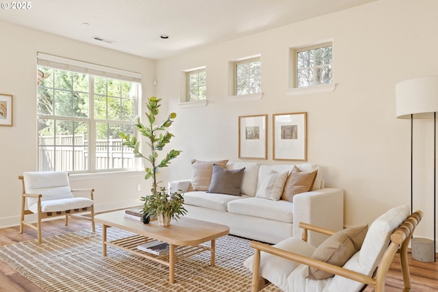 living room with visible vents, light wood-type flooring, and baseboards