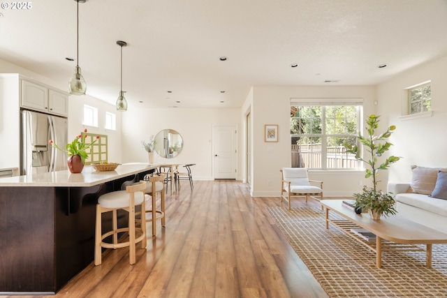 living area featuring light wood finished floors, baseboards, and recessed lighting