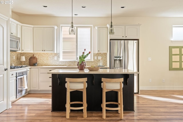 kitchen featuring decorative backsplash, a kitchen breakfast bar, a center island, and stainless steel appliances