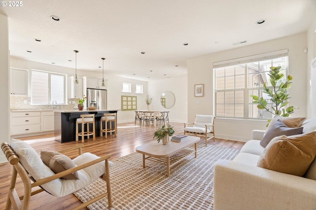 living area with recessed lighting, plenty of natural light, light wood-style floors, and visible vents