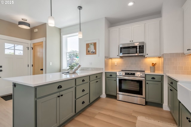 7257 SE Duke St Unit 3, Portland, OR 97206 - kitchen featuring appliances with stainless steel finishes, a peninsula, green cabinetry, light countertops, and recessed lighting