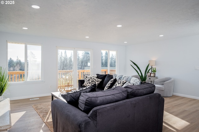 living room with light wood finished floors, baseboards, a textured ceiling, and recessed lighting