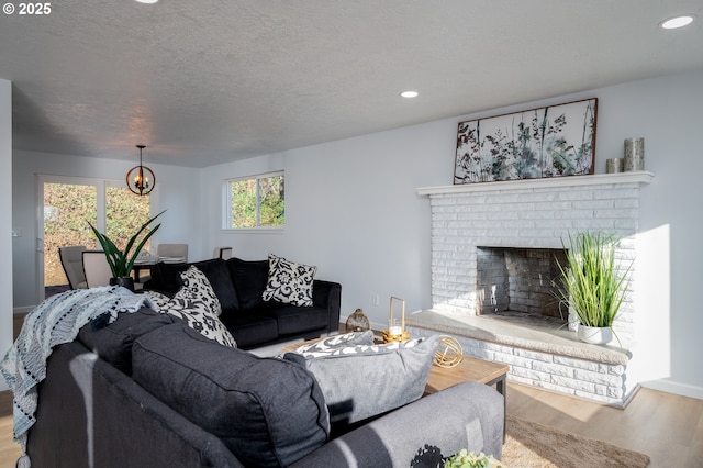 living room featuring a fireplace, recessed lighting, a textured ceiling, wood finished floors, and baseboards