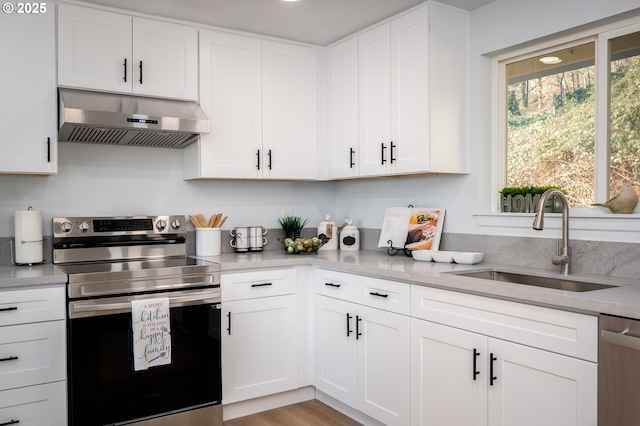 kitchen with appliances with stainless steel finishes, light countertops, under cabinet range hood, white cabinetry, and a sink