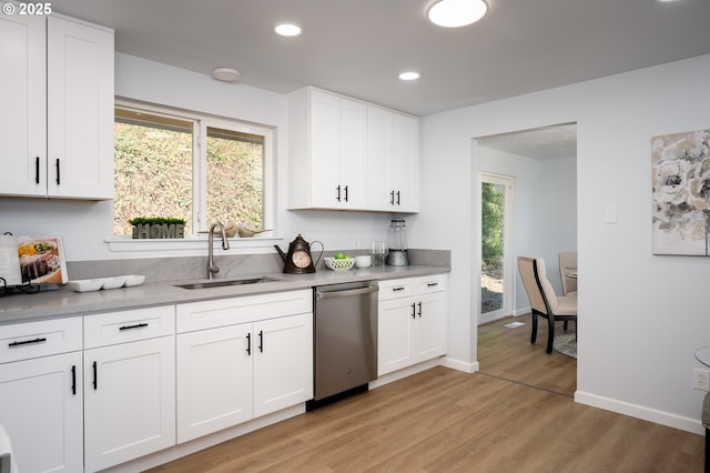 kitchen with plenty of natural light, a sink, light wood-style flooring, and stainless steel dishwasher