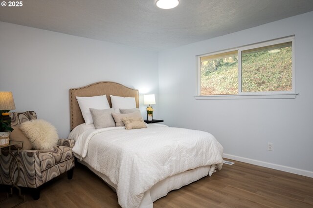 bedroom featuring a textured ceiling, wood finished floors, and baseboards