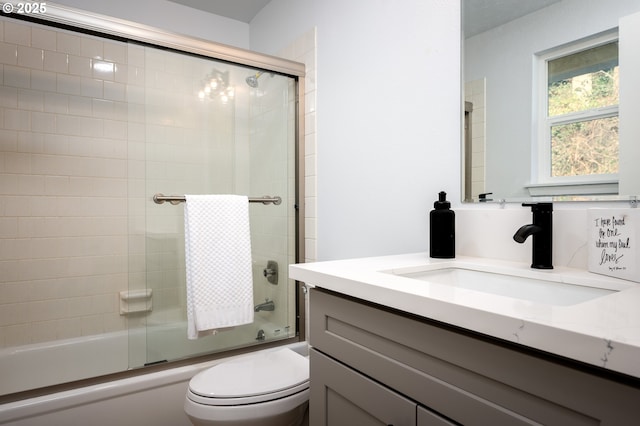 full bath featuring toilet, bath / shower combo with glass door, and vanity