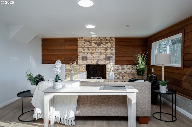 interior space with a fireplace, wood finished floors, visible vents, and baseboards