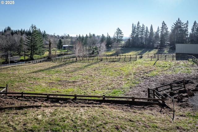 view of yard with fence, an outdoor structure, and a rural view