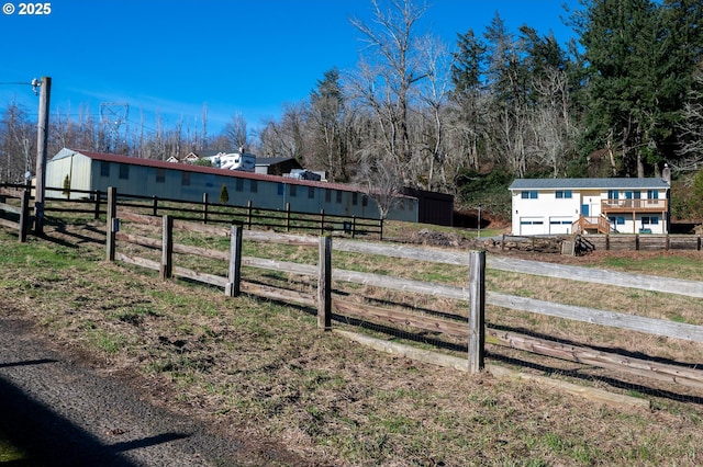 view of yard featuring a pole building, a rural view, an outdoor structure, and fence