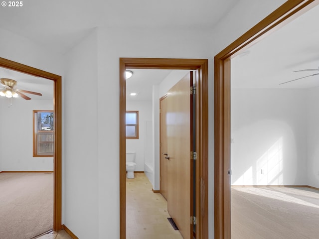 hall featuring light carpet and baseboards