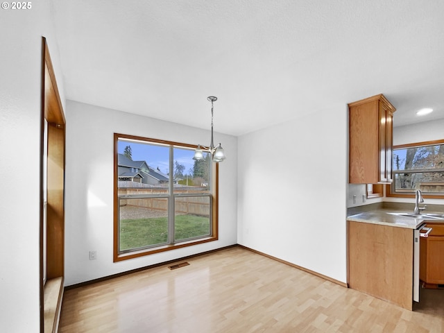 dining area featuring light wood finished floors, an inviting chandelier, visible vents, and baseboards