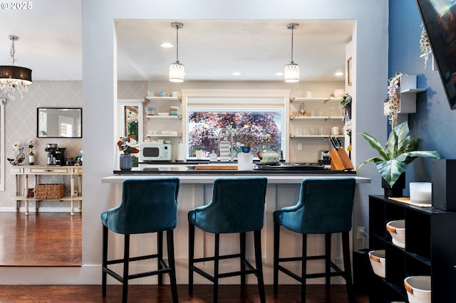 bar featuring wood finished floors, pendant lighting, and white microwave