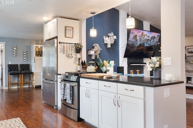 kitchen featuring dark countertops, white cabinetry, dark wood finished floors, decorative light fixtures, and stainless steel appliances