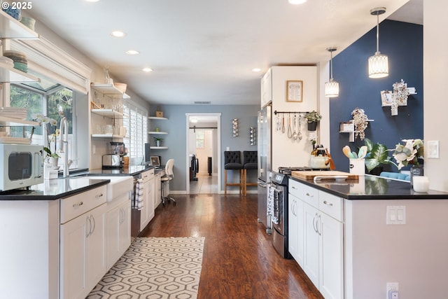 kitchen with dark wood-style flooring, dark countertops, appliances with stainless steel finishes, open shelves, and white cabinets