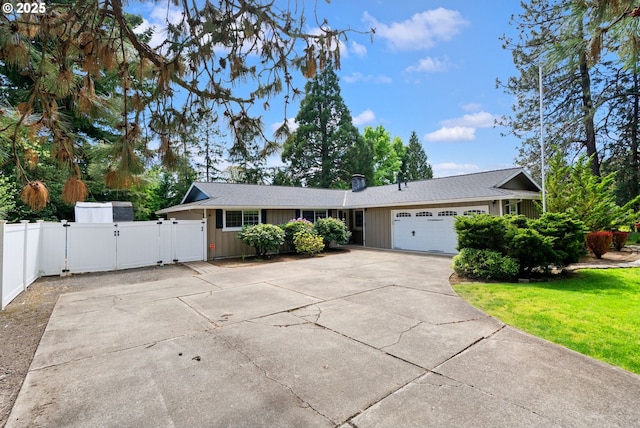 ranch-style house featuring a garage, a front yard, a gate, board and batten siding, and concrete driveway