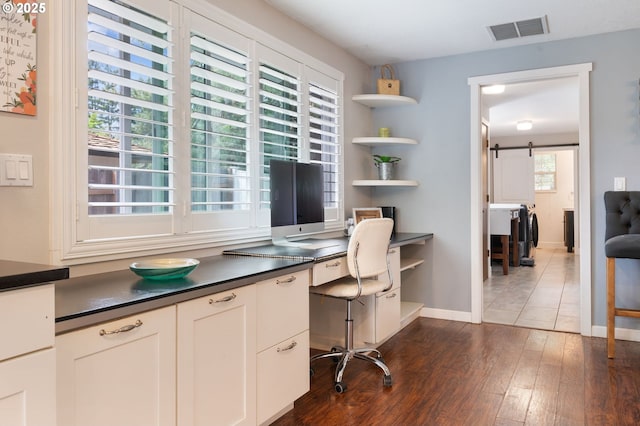 home office featuring visible vents, dark wood finished floors, a barn door, built in study area, and baseboards