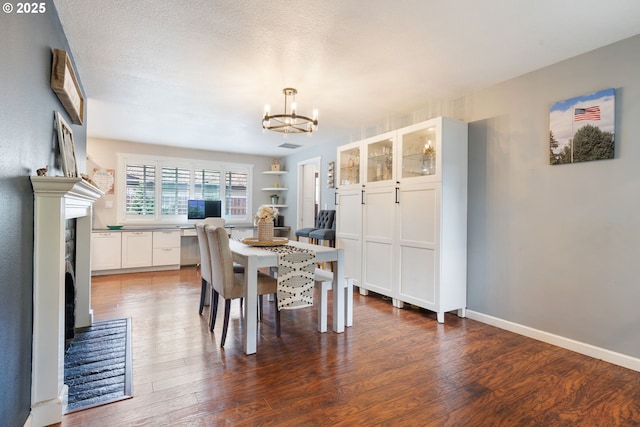 dining space with an inviting chandelier, baseboards, a fireplace, and wood finished floors
