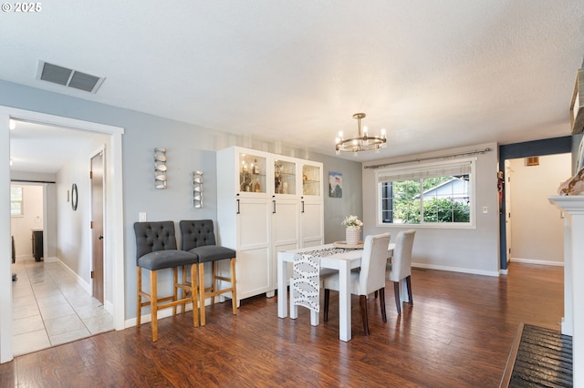 dining area featuring an inviting chandelier, baseboards, wood finished floors, and visible vents