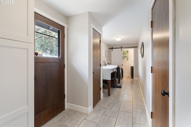 foyer featuring baseboards, a barn door, and plenty of natural light